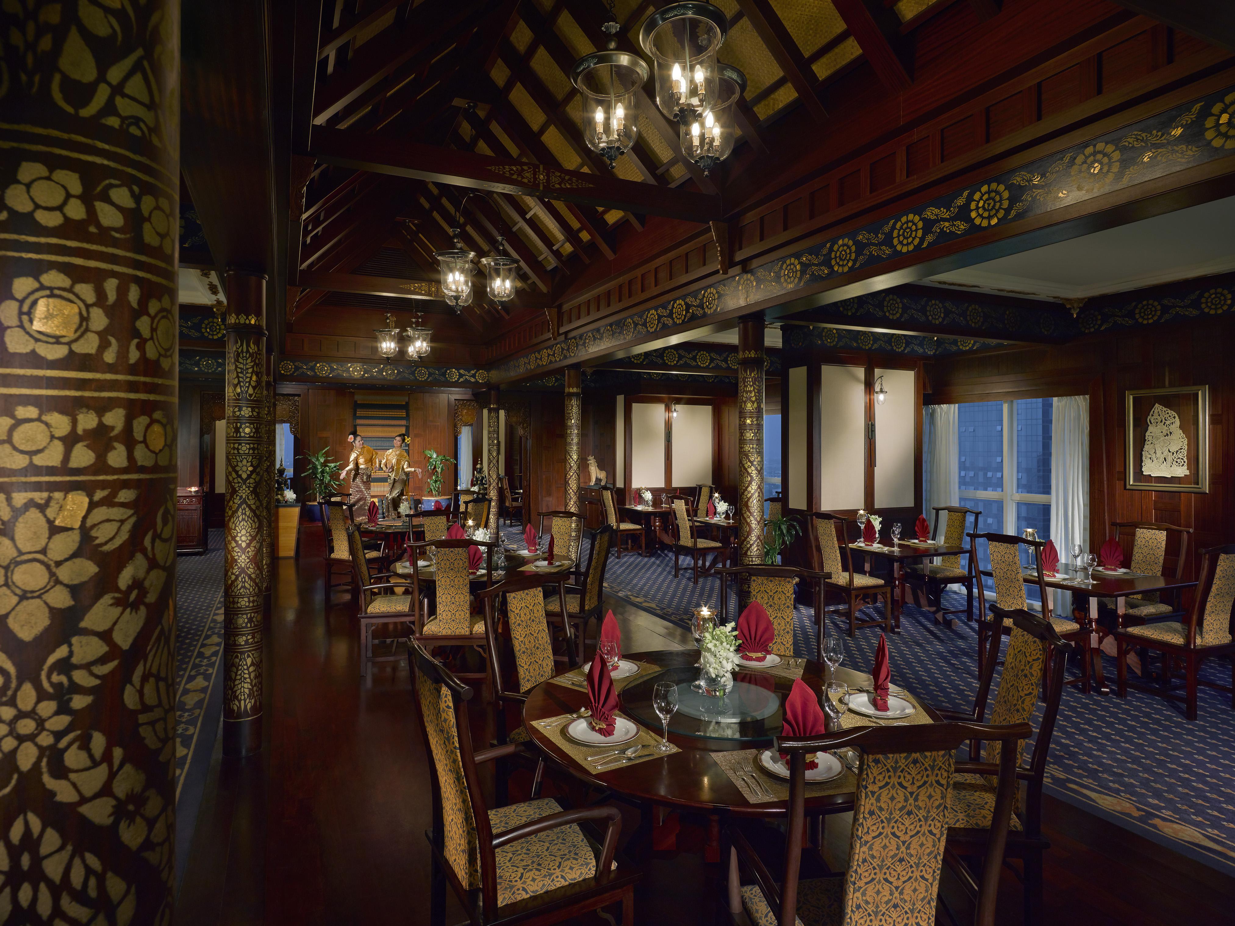 Dusit Thani Dubai Exterior photo The photo displays an elegantly designed restaurant interior. The space features wooden interiors with intricate decorative details, including floral patterns on the columns. The ceiling has a high, vaulted structure, and lighting fixtures provide a 